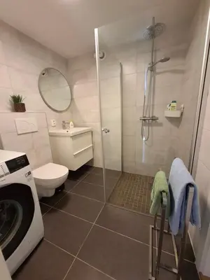 a bathroom with a shower and a washing machine at Nature View Apartment in Espeland in Bergen