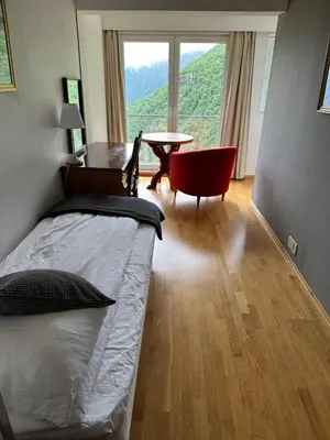 a bedroom with a bed and a table and a window at Hotel Videseter in Stryn