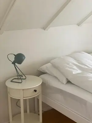 a bed with a nightstand and a lamp on a side table at Indreli feriehus in Flåm