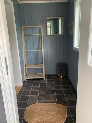 a room with a tiled floor with a shelf and a mirror at Halsteinsplassen in Surteberg