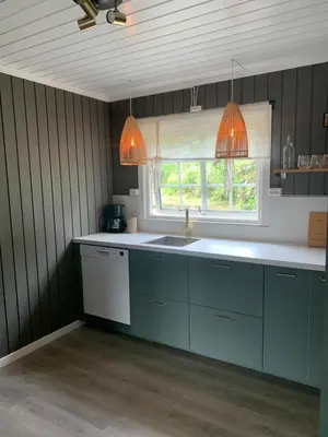 a kitchen with blue cabinets and a sink and a window at Halsteinsplassen in Surteberg