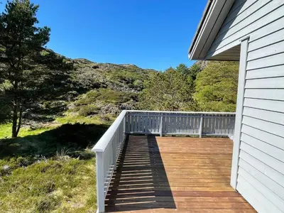 a wooden deck on the side of a house at 6 person holiday home in Espevær-By Traum in Espevær