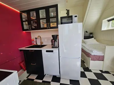 a small kitchen with a refrigerator and a bed at Rødseth gårdsovernatting Dobbeltrom in Molde