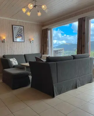 a living room with couches and a table and windows at In the middle of Trysil fjellet - Welcome Center - Apartment with 4 bedrooms and sauna - By bike arena and ski lift in Trysil