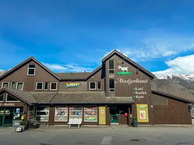 a store front of a building with mountains in the background at Langfoss in Etnesjøen
