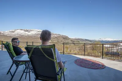 two people sitting in chairs on a deck looking at the mountains at Fosskamben 1 Moderne hytte ikkje langt frå Sogndal in Sogndal