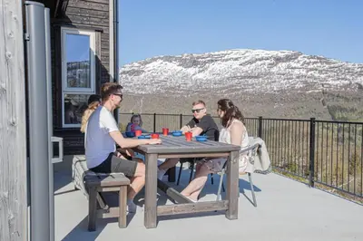 a group of people sitting around a wooden table on a deck at Fosskamben 1 Moderne hytte ikkje langt frå Sogndal in Sogndal