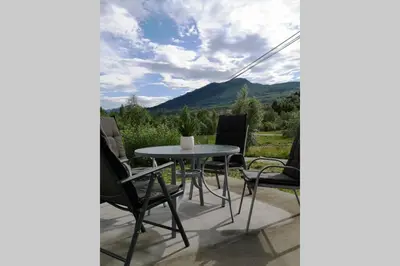 a table and chairs on a patio with mountains in the background at Casa Kleiv i Sogndalsdalen in Sogndal