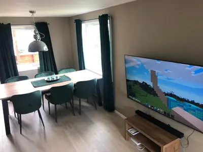 a dining room with a table and a large screen television at Atlantic Panorama Villa Kalle in Kristiansund