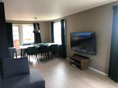 a living room with a television and a table with chairs at Atlantic Panorama Villa Kalle in Kristiansund