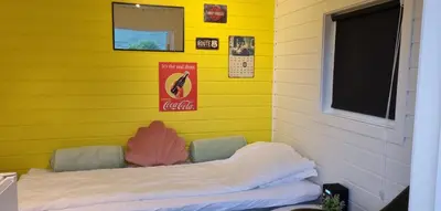 a room with a yellow wall with a couch at Rødseth gårdsovernatting Hytter in Molde