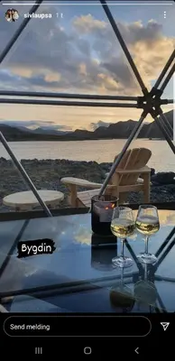 two glasses of wine on a table with a view of the ocean at Jotunheimen Arctic Domes in Beitostøl