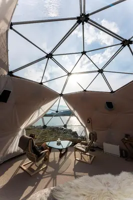 a person sitting in chairs in a room with a glass ceiling at Jotunheimen Arctic Domes in Beitostøl