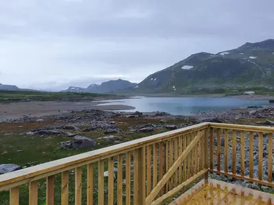 a wooden balcony with a view of a lake and mountains at Jotunheimen Arctic Domes in Beitostøl
