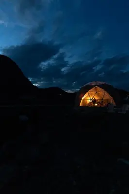 a lit up tent in a field at night at Jotunheimen Arctic Domes in Beitostøl