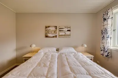 a white bed in a bedroom with two night stands at Flotunet - Jørnhuset in Stryn