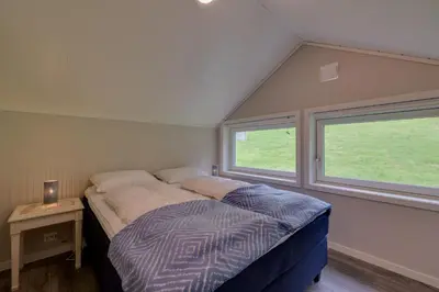 a bed in a small room with two windows at Flotunet - Jørnhuset in Stryn