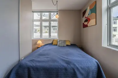 a bedroom with a blue bed and a window at Cozy apartment in Alesund city in Ålesund