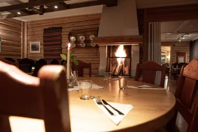 a wooden table in a restaurant with a fireplace at Raubergstulen fjellstue og hytter in Boverdalen