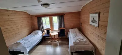 a room with two beds and a table and a window at Raubergstulen fjellstue og hytter in Boverdalen