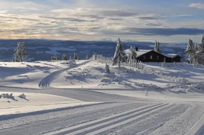 a snow covered slope with a house in the distance at Løstegård Cabins in Gol