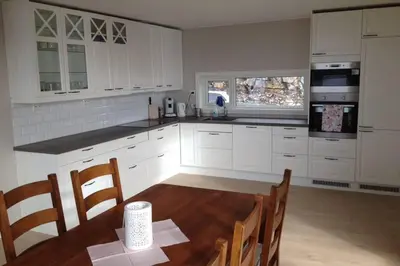 a kitchen with white cabinets and a table with chairs at Austefjordtunet 15 in Forland