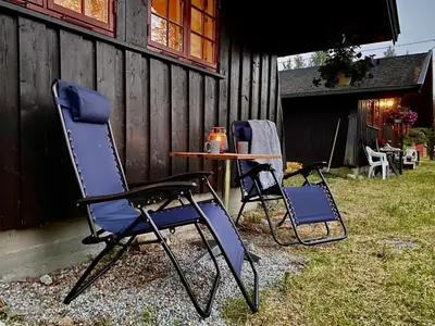 two chairs and a table in front of a building at Vennebo - Koselig liten hytte med alle fasiliteter in Ål