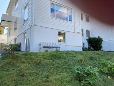 a white house with a bench in front of it at Kjellerleilighet - nært Haukeland sykehus. in Bergen