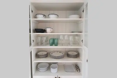 a white pantry with plates and dishes on shelves at Fantastic and high standard apartment in Nordseter in Lillehammer