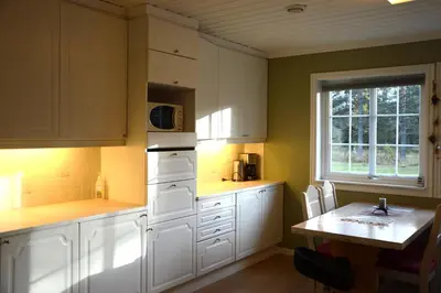 a kitchen with white cabinets and a table and a window at Fulufjellet nationalpark Lodge - Home of snow, nature and peace in Ljørdalen