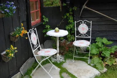 two chairs and a table in a garden at Regnbuegården in Røros