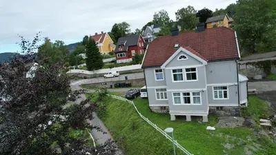 a white house with a red roof on a street at Lillehammer Camping - Sentrums leilighet in Lillehammer