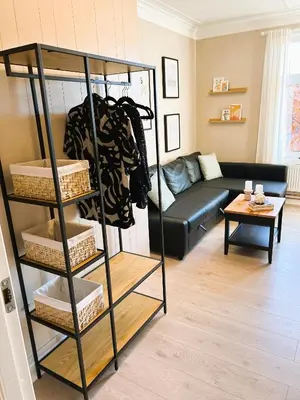 a black shelf in a living room with a couch at Lillehammer Camping - Sentrums leilighet in Lillehammer