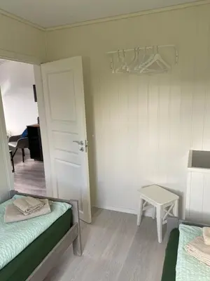 a room with two beds and a door and a table at Feriehus med Sjøutsikt in Sætra