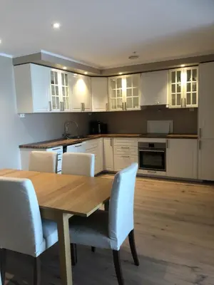 a kitchen with a wooden table and white cabinets at Ustedalen Resort Leiligheter in Geilo