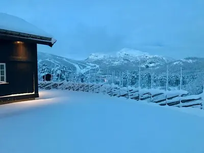a snow covered building with a mountain in the background at Kirkebøen Hytter in Hemsedal