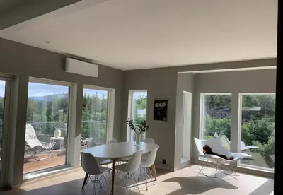 a dining room with a white table and chairs and windows at Villa with jacuzzi in Nord Bjørøy