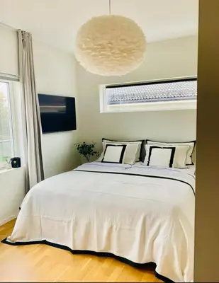 a bedroom with a large white bed and a chandelier at Villa with jacuzzi in Nord Bjørøy