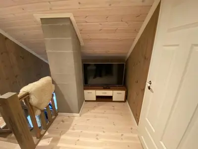a living room with a tv and a stairway with a stair at Endely - ski inn / ut in Rauland