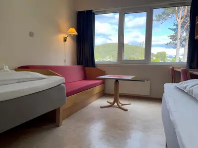 a hotel room with a red couch and a table at BORG Sommerhotell in Ålesund