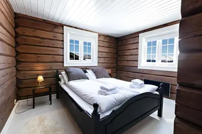 a bedroom with a bed in a room with wooden walls at Utsikten in Sykkylven