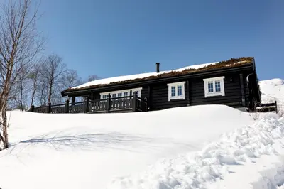 a log cabin with snow in front of it at Utsikten in Sykkylven