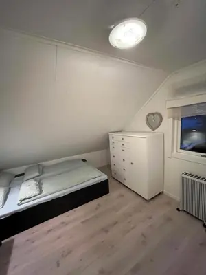 a bedroom with a bed and a dresser and a window at Hjelvikhytta - flott beliggenhet ved sjøen in Hjelvik