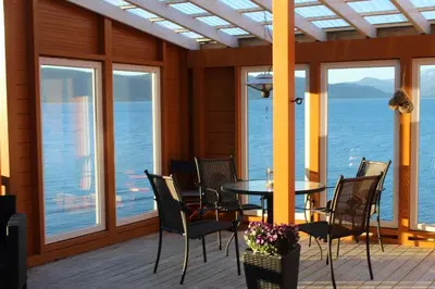 a dining room with a table and chairs and the ocean at Hjelvikhytta - flott beliggenhet ved sjøen in Hjelvik
