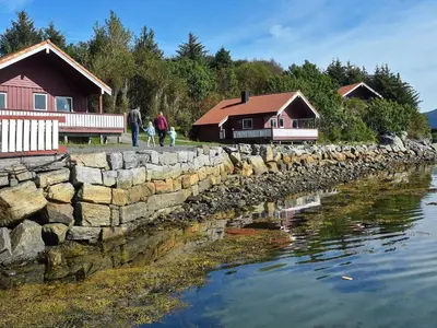 a group of people walking by a stone wall and houses at 6 person holiday home in Bud-By Traum in Bud
