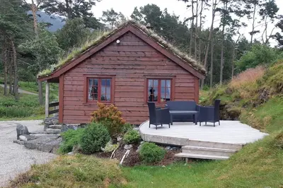 a small cabin with a table and chairs on a deck at Klævold utleigehytte in Klevoll