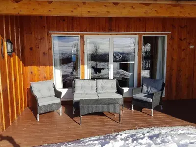 a porch with three chairs and a cat looking out the window at Magnesplass - Dagalifjell in Dagali