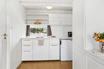 a white kitchen with white cabinets and a window at Topcamp Onsakervika - Tyrifjorden in Svensrud