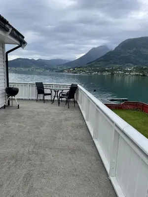 a porch with chairs and a table and a view of a lake at Fjord Apartments in Dimmelsvik
