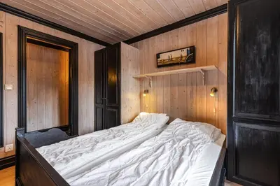 a large bed in a room with wooden walls at Tinden Apartments in Hemsedal